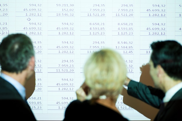 A chart comparing the current tax rates with the proposed tax rates for individuals and corporations, displayed on a tablet with a stylus next to it. The background shows a blurred image of a busy financial district.