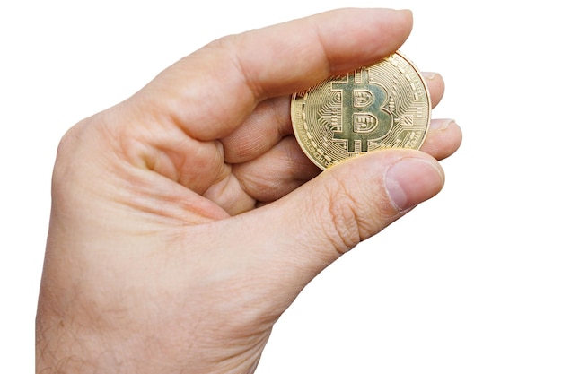 A close-up of a person's hand holding a physical representation of a Bitcoin, with a tax form partially visible in the background. The lighting is dramatic, highlighting the contrast between the tangible coin and the abstract concept of tax obligations.