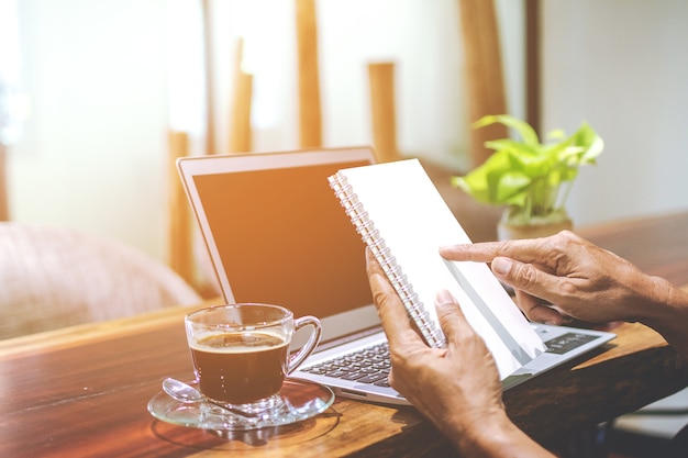 A person using a laptop at home, with a cup of coffee and a notepad nearby. The laptop screen displays a student loan forgiveness application form. The scene is warm and inviting, suggesting a comfortable and focused work environment.