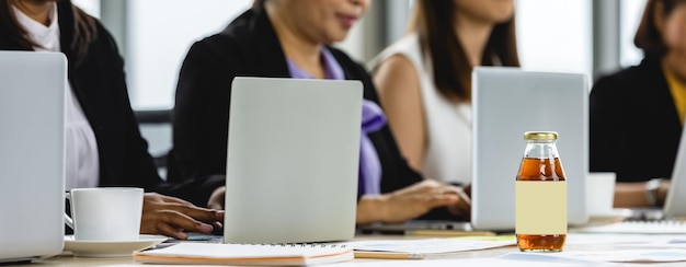 A group of people filling out application forms at a table with laptops during a job training program information session. The setting is a community center with brochures and program materials.